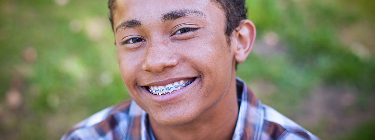 Adolescente sorridente com aparelho ortodôntico em um parque.
