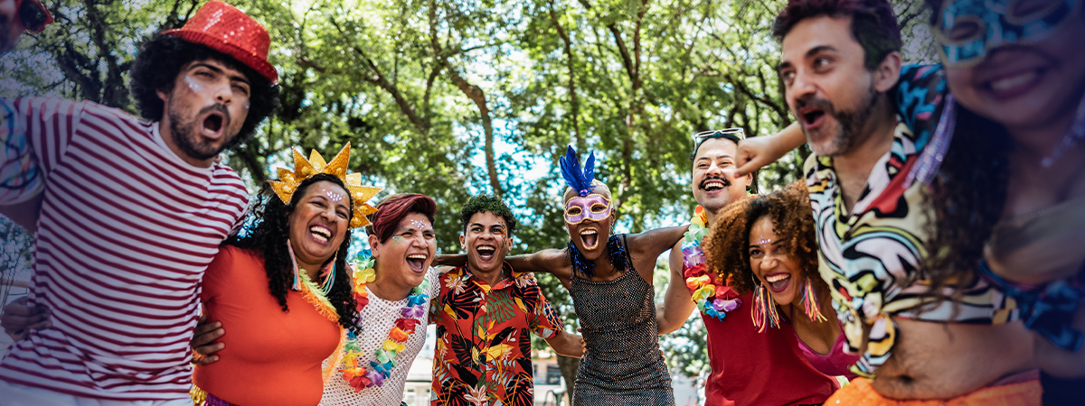Grupo alegre em festa de carnaval ao ar livre, com fantasias coloridas e máscaras