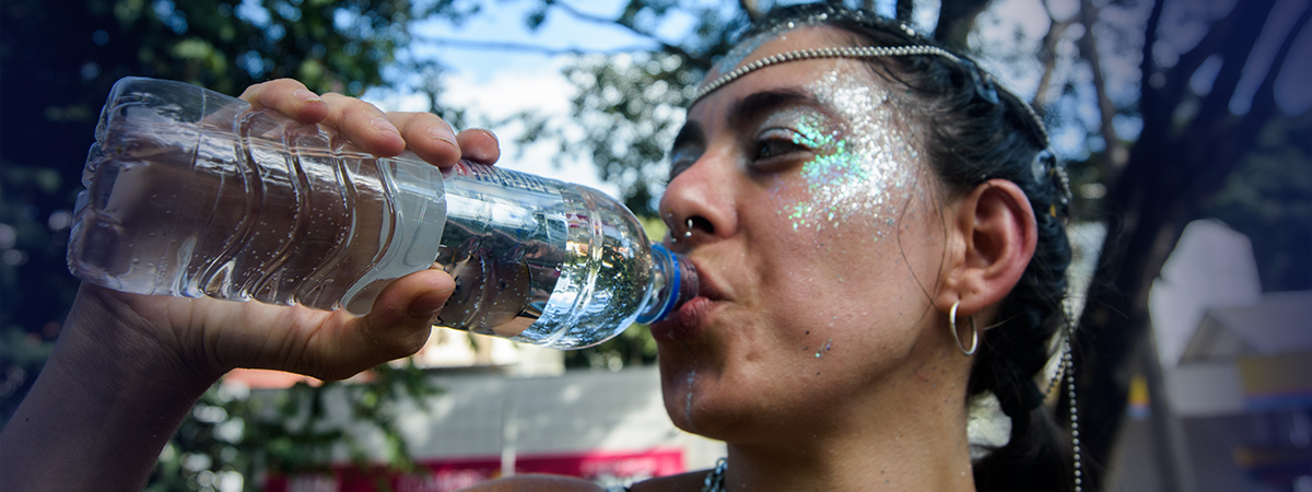 Mulher bebendo água e refrescando-se durante o carnaval
