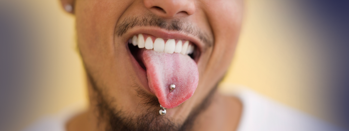 Homem sorridente mostrando a língua com piercing.