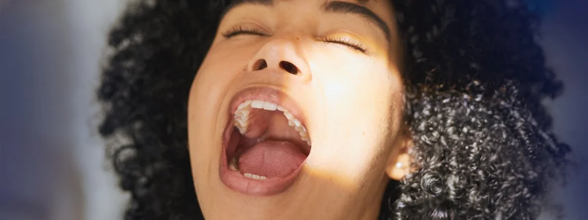 Mulher jovem com a boca aberta em um consultório dentário. 