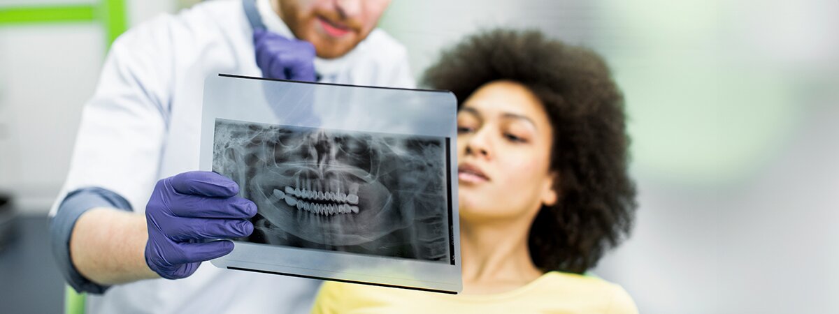 Dentista mostrando uma radiografia panorâmica para paciente feminina em uma clínica.