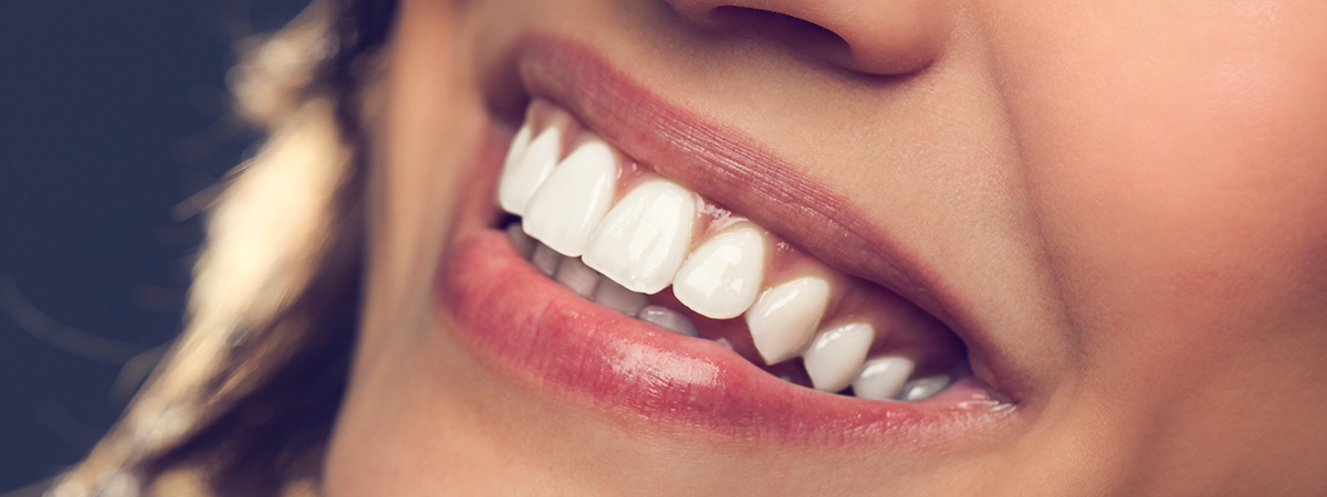 Estética rosa: Sorriso feminino com dentes brancos e batom rosa, close-up parcial do rosto.