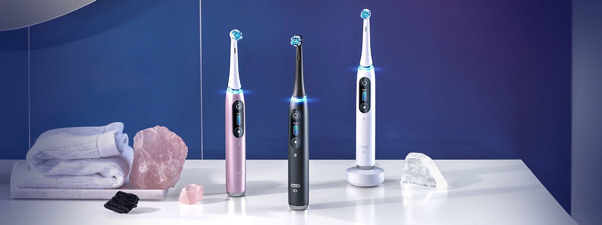 Escovas de dentes elétricas em bancada com toalhas e cristais decorativos como sugestão para prevenir halitose