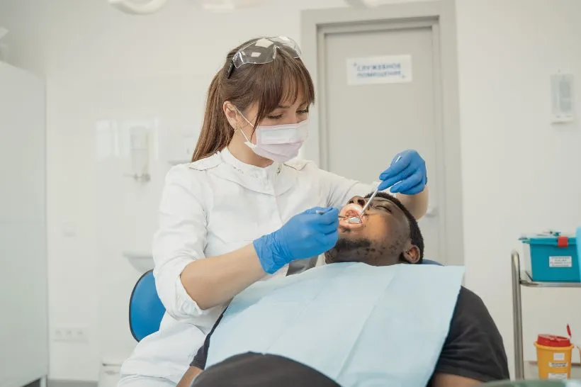 Dentista examinando o dente de um paciente masculino verificando se o dente cariado necessita de um tratamentode canal em uma clínica moderna