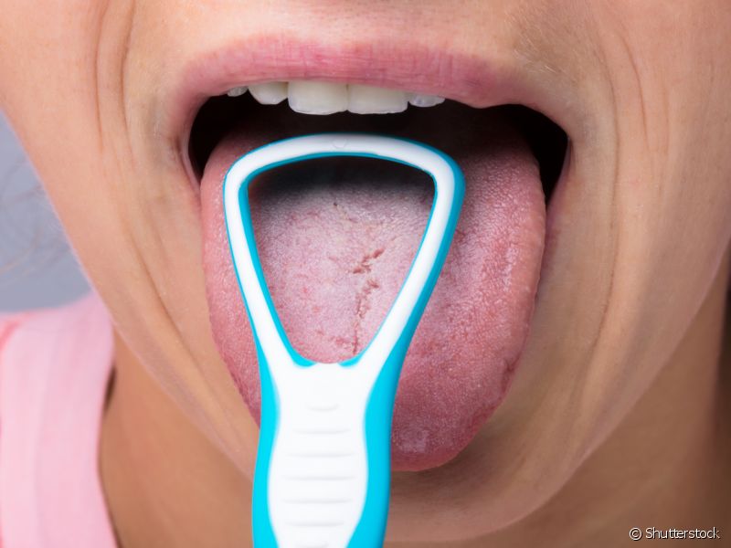 Faça a limpeza da língua com ajuda de um raspador ou limpador específico para região.