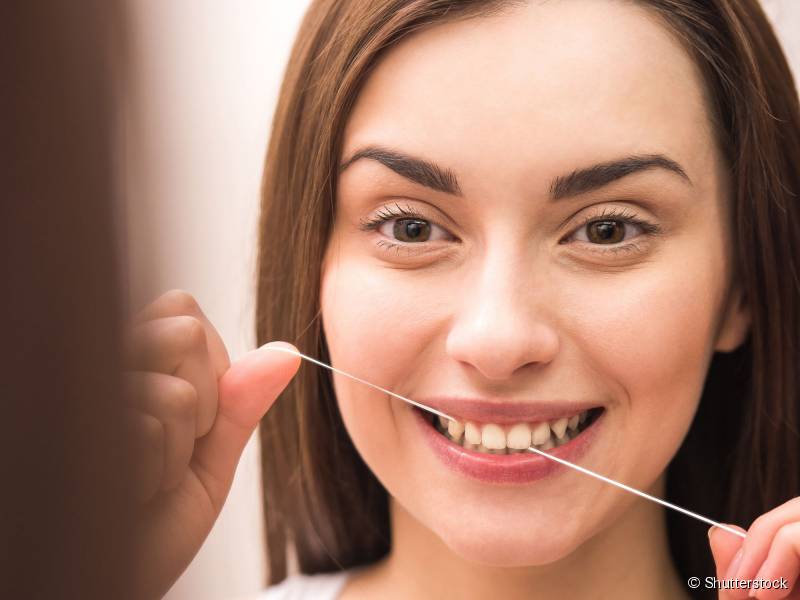 Antes de começar a escovar o ideal é pegar um generoso pedaço de fio dental e passar entre todos os dentes para tirar os resíduos de alimentos.